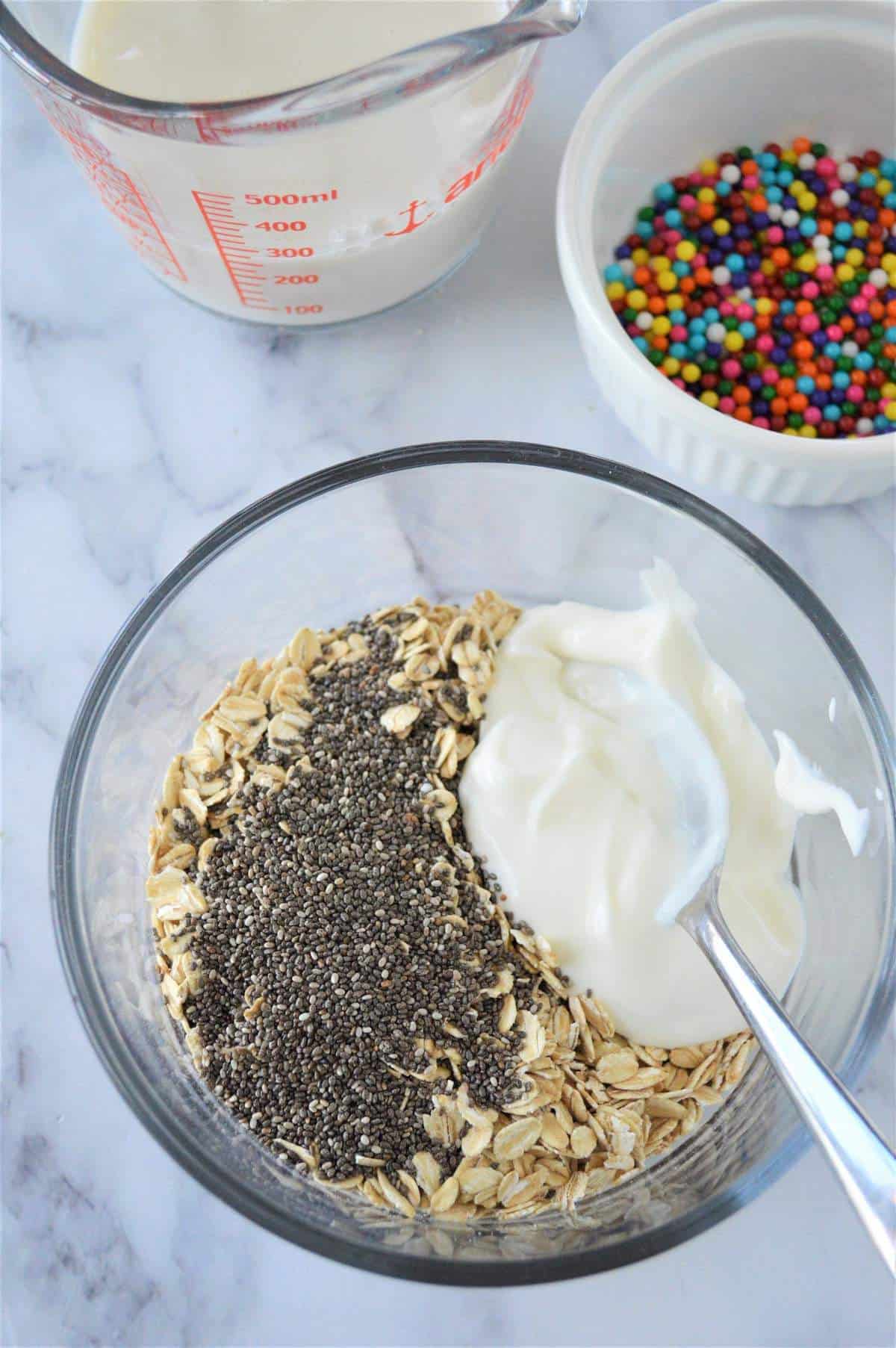 A bowl of oats and chia seeds with a scoop of greek yogurt being mixed into it.